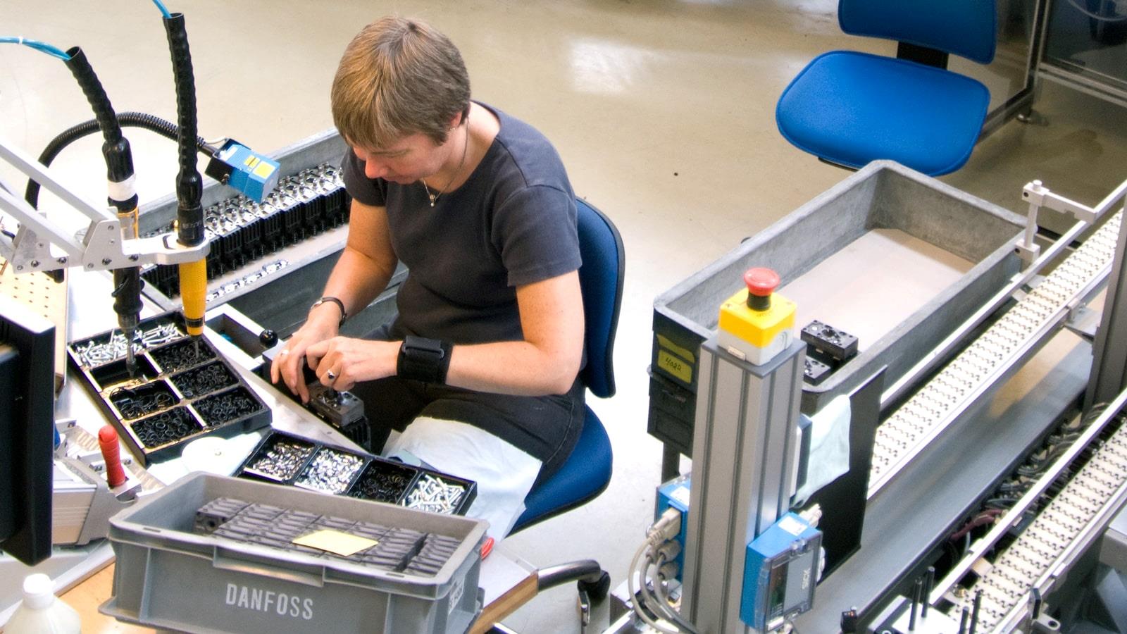 Female worker assembles components at Sauer-Danfoss